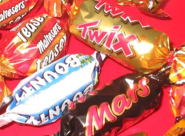 A Twix, Bounty, Mars, and Maltesers wrapper against a red background.
